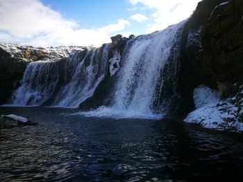 Scenic view of waterfall against sky