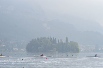 People on mountain by lake against sky