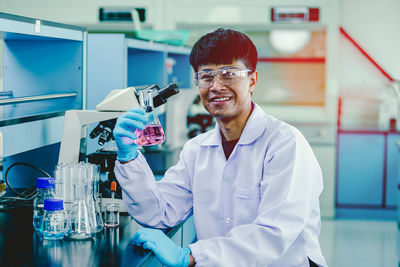 Cautious professional chemistry laboratory worker having erlenmeyer glass jars,medium shot.