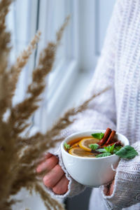 Female hands on sweater holding tea with lemon, cinnamon sticks and mint leaves. hot drink. healthy