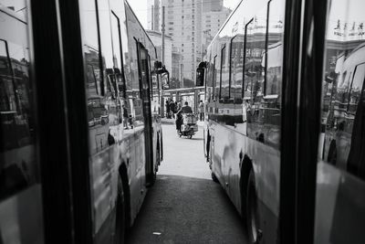 Man riding moped on street seen through buses