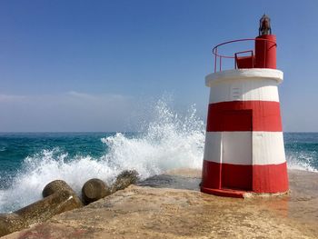 Lighthouse by sea against sky