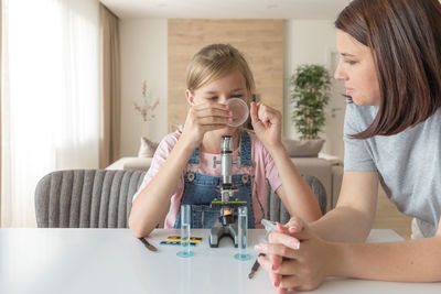 Mother helping daughter in science project at home