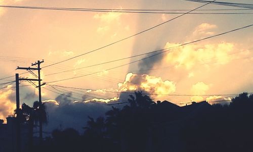 Low angle view of electricity pylon against cloudy sky