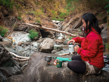 Side view of woman sitting on rock
