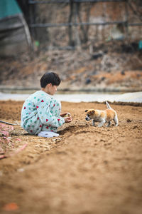 Rear view of boy sitting on land