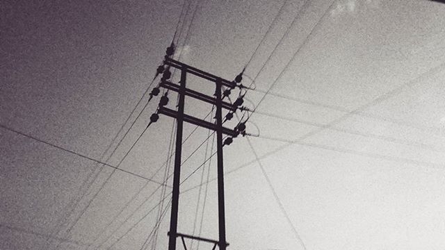 low angle view, electricity, technology, power line, power supply, fuel and power generation, cable, electricity pylon, connection, built structure, sky, clear sky, no people, day, architecture, outdoors, lighting equipment, power cable, sunlight, building exterior