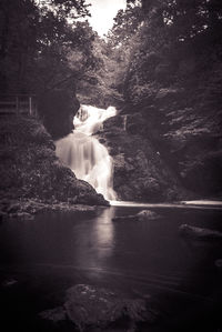 Scenic view of waterfall in forest against sky