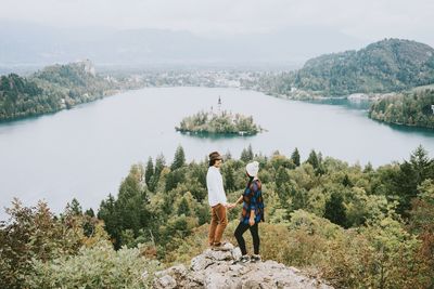 Rear view of friends standing on rock in forest