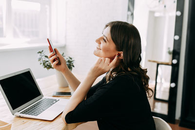 Side view of young woman using mobile phone