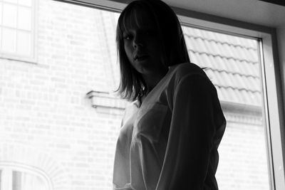 Side view of young woman looking through window