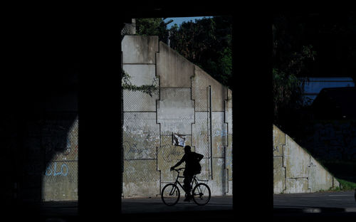 Silhouette man riding bicycle on building