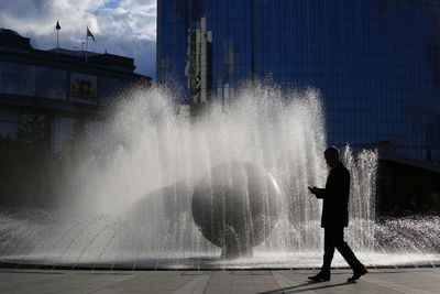 Man standing by fountain in city
