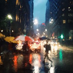 Close-up of wet illuminated city street during rainy season