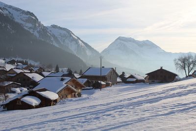 Snow covered houses and mountains against sky