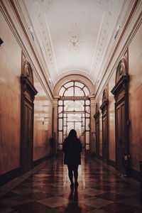 Rear view of woman walking in corridor of building