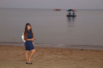 Young woman on beach against sky