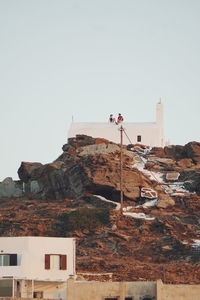 People sitting on roof of church against clear sky