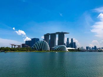 City buildings at waterfront against cloudy sky