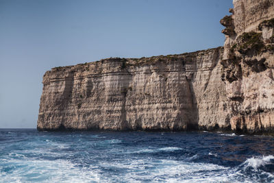 View of cliff by sea against clear sky