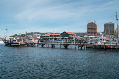Boats moored in harbor against buildings in city