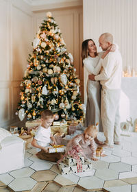 A family with children celebrate give gift boxes decorate a christmas tree in the interior the house