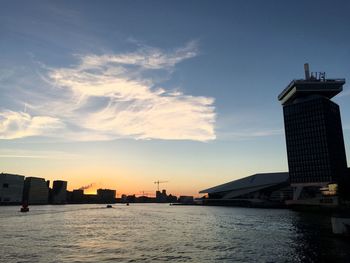 River by city against sky during sunset