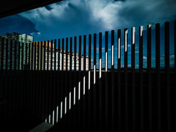 Metal fence by building against sky