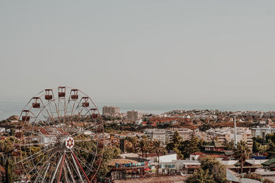 Ferris wheel in city against clear sky