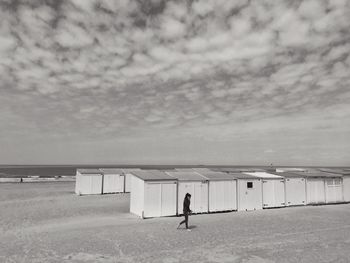 People at seaside against cloudy sky