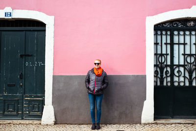 Full length of smiling woman standing against wall