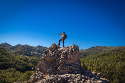 Rear view of man standing on mountain against clear blue sky