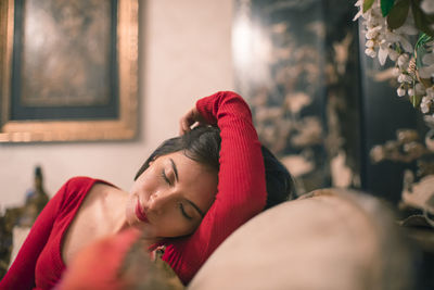 Young woman wearing red bodysuit on sofa at home