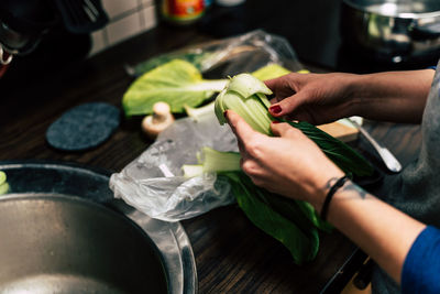 Cropped hands of woman cleaning vegetable at home