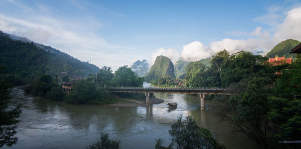 Bridge over river against cloudy sky