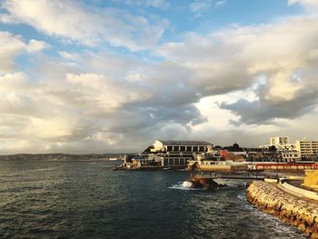 Scenic view of sea by buildings against sky