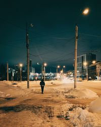 Rear view of man walking on road at night