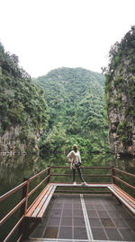 Full length of woman standing by railing against lake