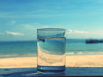 Close-up of drink on beach against sky