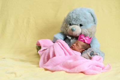 Baby girl with teddy bear and blanket on sofa