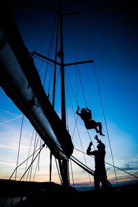 Low angle view of silhouette people sailing on ship