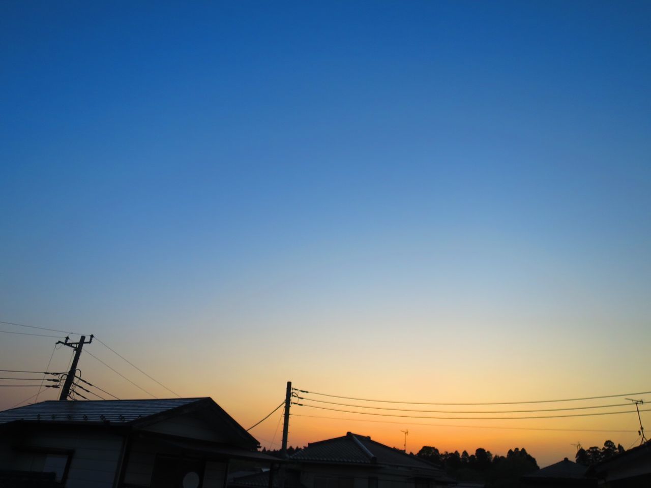 SILHOUETTE HOUSES AND ELECTRICITY PYLON AGAINST CLEAR SKY