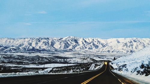 Road amidst snowcapped mountains against sky