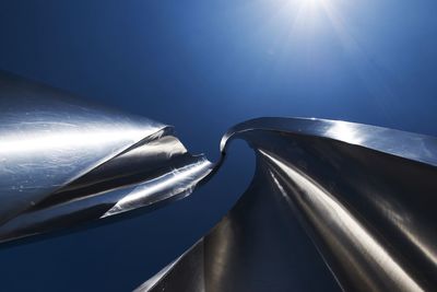 Low angle view of metal art against blue sky