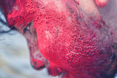 Close-up of man with covered face in red powdered paint