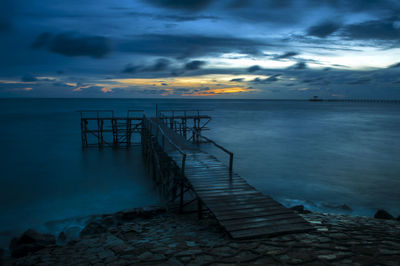 Pier over sea against dramatic sky