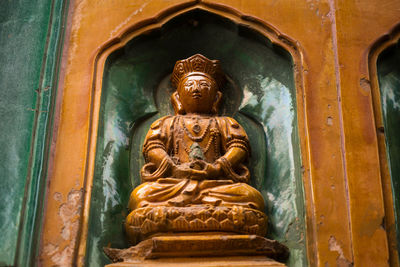 Low angle view of buddha statue against building