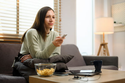 Young woman using phone while sitting at home