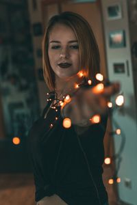 Portrait of woman standing by illuminated lighting equipment