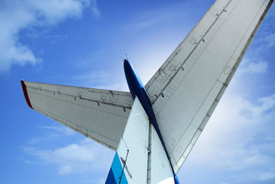 Low angle view of airplane wing against blue sky